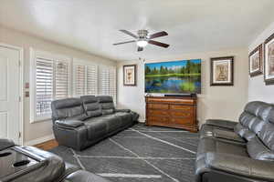 Living room featuring ceiling fan and a textured ceiling