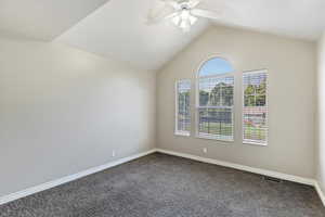Unfurnished room with dark carpet, vaulted ceiling, and ceiling fan