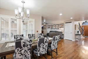 Dining room with hardwood / wood-style flooring and ceiling fan with notable chandelier