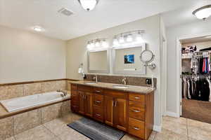 Bathroom with tile patterned floors, vanity, and tiled tub