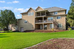 Rear view of house with a lawn, stucco siding, and stairway