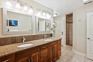 Bathroom with tile patterned floors, vanity, and a tile shower