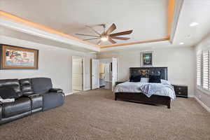 Bedroom featuring crown molding, ceiling fan, a tray ceiling, and carpet