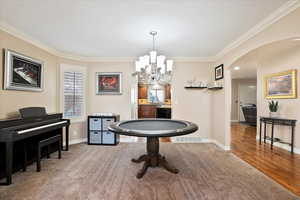 Carpeted dining area with ornamental molding and an inviting chandelier