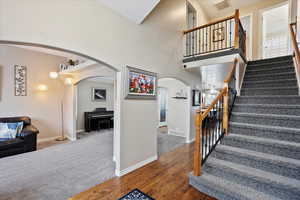 Stairs with hardwood / wood-style flooring and a high ceiling