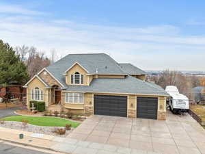 Traditional home featuring stone siding, driveway, roof with shingles, and a garage