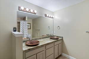 Bathroom featuring double vanity, light tile patterned floors, curtained shower, and a textured ceiling