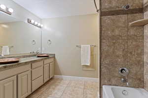 Bathroom featuring tile patterned flooring, vanity, and tiled shower / bath combo