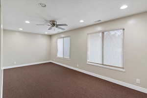 Empty room featuring dark colored carpet, recessed lighting, healthy amount of natural light, and ceiling fan