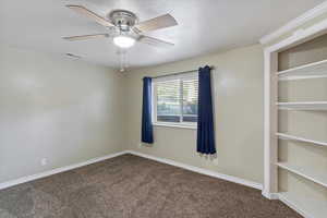 Carpeted empty room featuring baseboards and a ceiling fan