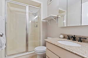 Bathroom with vanity, toilet, a shower with shower door, and tile patterned flooring