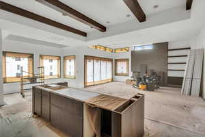 Kitchen featuring beam ceiling, dark brown cabinets, and a kitchen island