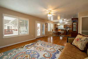 Living room with vaulted ceiling, ceiling fan, and hardwood / wood-style floors