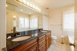 Primary Bathroom with vanity, a bath, tile patterned floors, and toilet