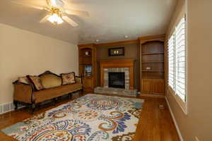 Living room with dark hardwood / wood-style flooring, a fireplace, and ceiling fan