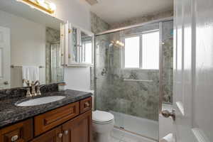 Bathroom featuring vanity, tile patterned flooring, toilet, and walk in shower