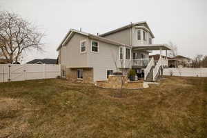 Back of property featuring a wooden deck and a lawn