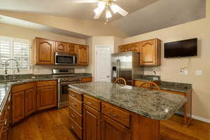 Kitchen featuring a kitchen island, dark hardwood / wood-style floors, lofted ceiling, sink, and stainless steel appliances