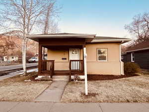 Bungalow-style house featuring covered porch and stucco siding