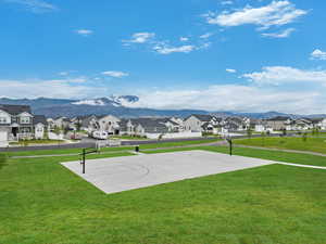 View of sport court with a mountain view and a lawn