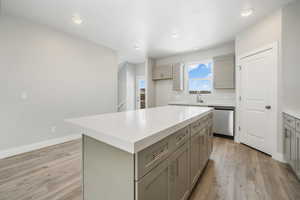 Kitchen with gray cabinetry, light hardwood / wood-style flooring, stainless steel dishwasher, and a center island