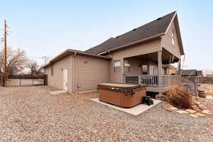 Rear view of house featuring a hot tub and a covered deck