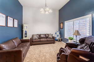 Carpeted living room with a chandelier