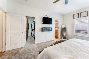 Master bedroom featuring ensuite bathroom, a spacious closet, carpet, ceiling fan, and a walk-in closet