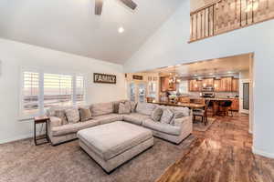 Family  room with laminate and carpet flooring, high vaulted ceiling, and ceiling fan