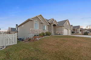 View of front of home featuring a yard, a garage, and central AC