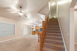 Stairway featuring vaulted ceiling, ceiling fan, and carpet flooring