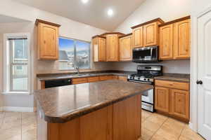 Kitchen with stainless steel appliances, a kitchen island, sink, and lofted ceiling