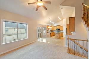 Living room featuring ceiling fan with notable chandelier, lofted ceiling, and light colored carpet