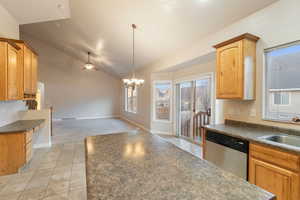 Kitchen featuring vaulted ceiling, light tile patterned flooring, decorative light fixtures, dishwasher, and sink