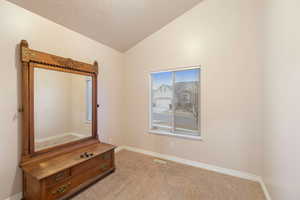 Unfurnished bedroom featuring lofted ceiling and light carpet