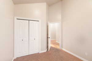 Unfurnished bedroom featuring light carpet and a closet