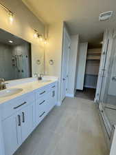 Bathroom with tile patterned flooring, vanity, a textured ceiling, and walk in shower