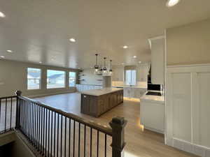 Kitchen featuring pendant lighting, sink, white cabinets, a kitchen island, and light wood-type flooring