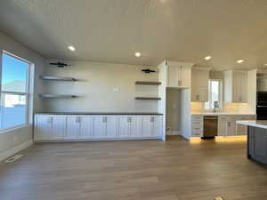 Kitchen featuring white cabinetry, stainless steel appliances, light hardwood / wood-style floors, and backsplash