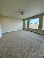 Carpeted empty room with a textured ceiling and ceiling fan