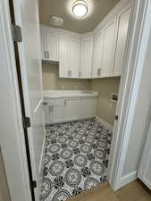 Laundry area with cabinets, hookup for a washing machine, light tile patterned floors, and a textured ceiling