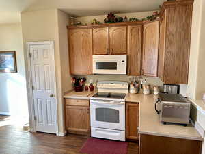 Kitchen with white appliances and dark hardwood / wood-style flooring