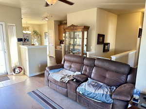 Living room with ceiling fan with notable chandelier, track lighting, light hardwood / wood-style floors, and a textured ceiling