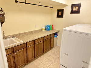 Laundry room with independent washer and dryer, sink, and light tile patterned floors