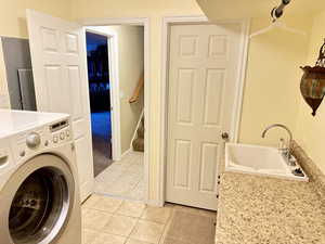 Laundry area with light tile patterned flooring, washer / clothes dryer, and sink