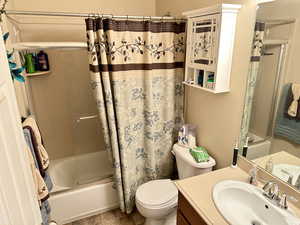 Full bathroom featuring shower / tub combo with curtain, vanity, and toilet