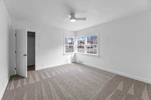 Master bedroom with ceiling fan, a spacious closet, and carpet