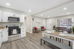 Kitchen with appliances with stainless steel finishes, light hardwood / wood-style flooring, and white cabinets