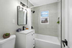 Full bathroom with vanity, shower / bath combo with shower curtain, and toilet