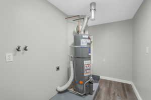 Utility room featuring strapped water heater